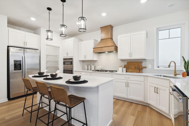 kitchen with backsplash, a center island, premium range hood, appliances with stainless steel finishes, and a sink