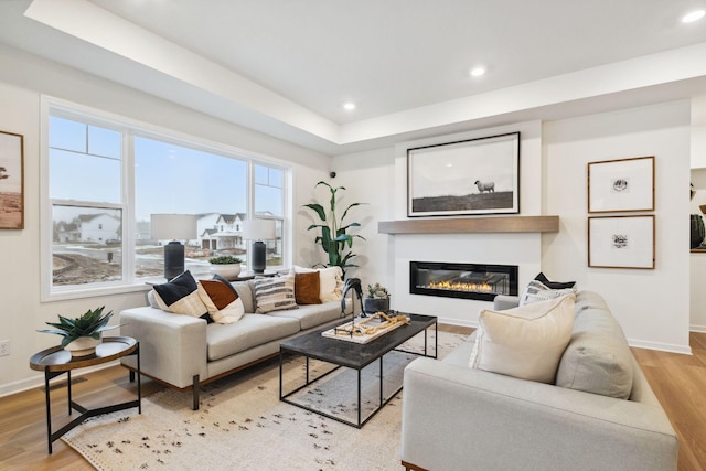 living room with a glass covered fireplace, light wood-style flooring, recessed lighting, and baseboards