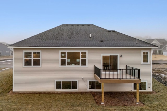 rear view of property featuring a lawn and a shingled roof