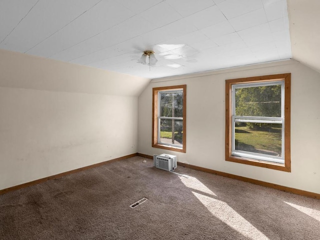 additional living space with an AC wall unit, carpet floors, and vaulted ceiling