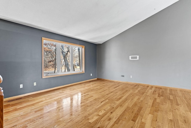 spare room with lofted ceiling and light wood-type flooring