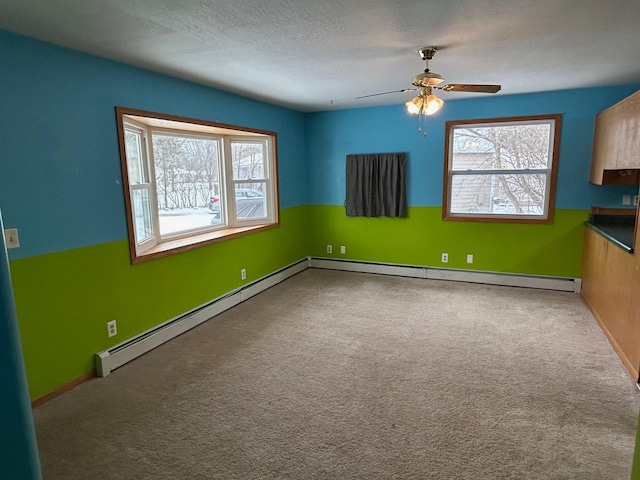 empty room with carpet floors, a baseboard radiator, plenty of natural light, and ceiling fan