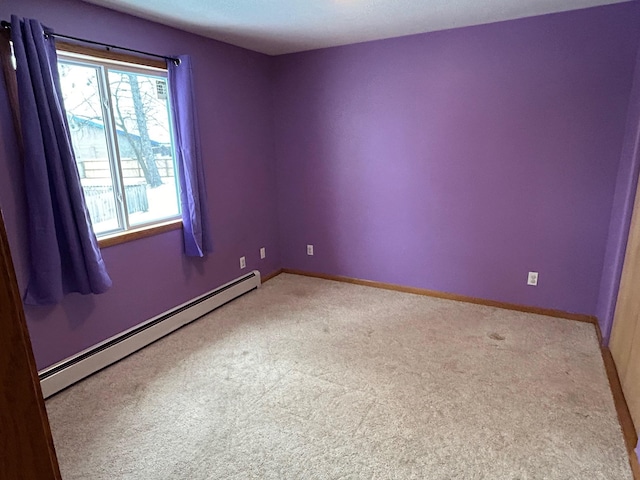 spare room featuring light colored carpet and a baseboard heating unit