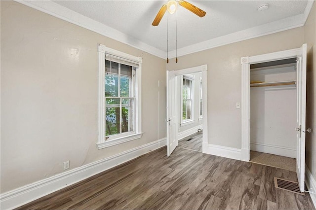 unfurnished bedroom with ceiling fan, wood-type flooring, a textured ceiling, a closet, and ornamental molding