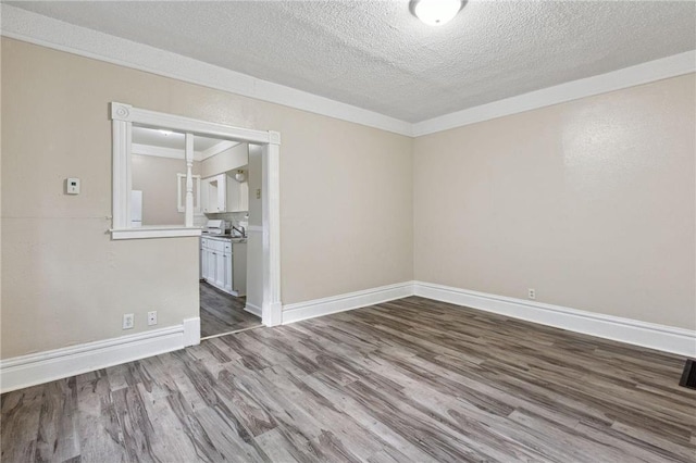 spare room featuring crown molding, wood-type flooring, and a textured ceiling