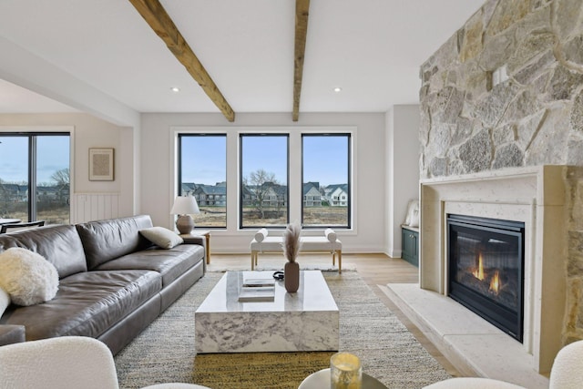 living room with beam ceiling, light wood-type flooring, and a fireplace