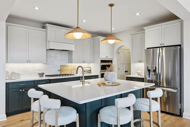 kitchen featuring decorative backsplash, appliances with stainless steel finishes, sink, white cabinets, and hanging light fixtures