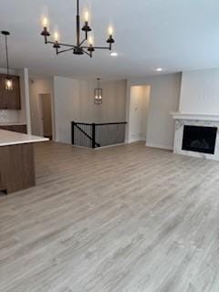 unfurnished living room with a notable chandelier and light wood-type flooring