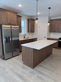 kitchen featuring stainless steel fridge with ice dispenser, light hardwood / wood-style floors, pendant lighting, and sink