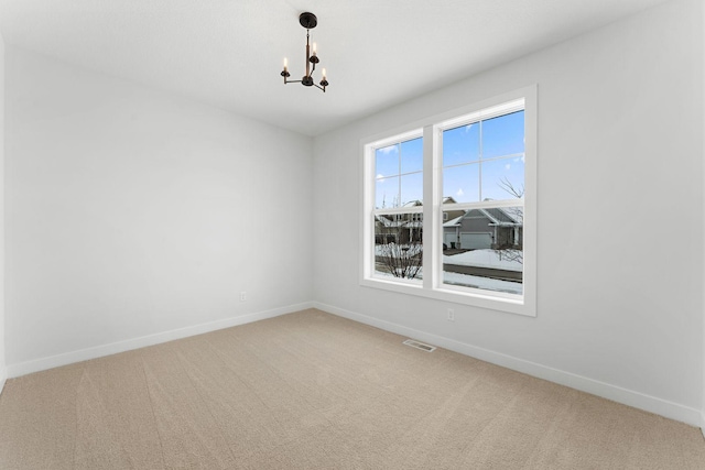 carpeted spare room with an inviting chandelier