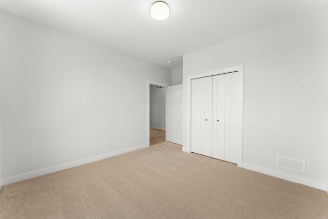 unfurnished bedroom with a closet and light carpet