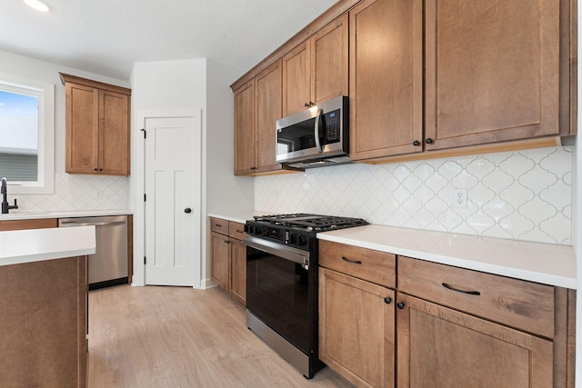 kitchen featuring appliances with stainless steel finishes, sink, backsplash, and light hardwood / wood-style floors