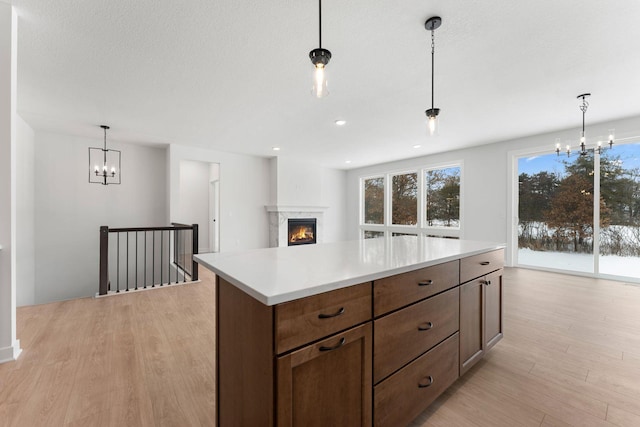 kitchen featuring light hardwood / wood-style flooring, a notable chandelier, a textured ceiling, a kitchen island, and decorative light fixtures