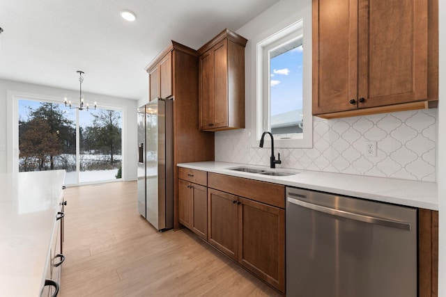 kitchen with sink, plenty of natural light, stainless steel appliances, light hardwood / wood-style floors, and decorative light fixtures