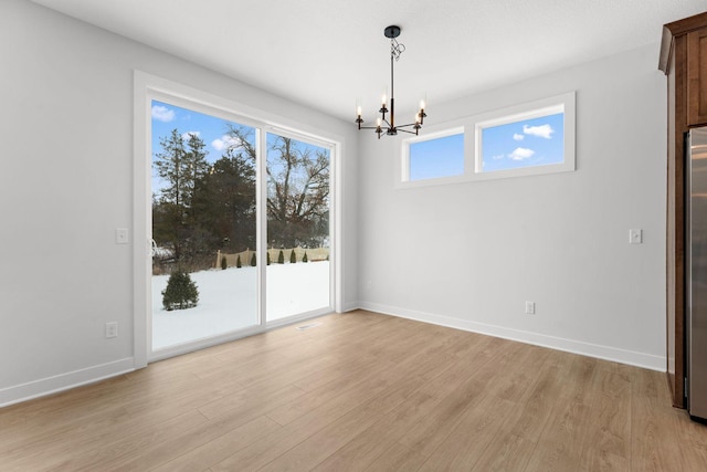 unfurnished dining area with a chandelier and light hardwood / wood-style floors