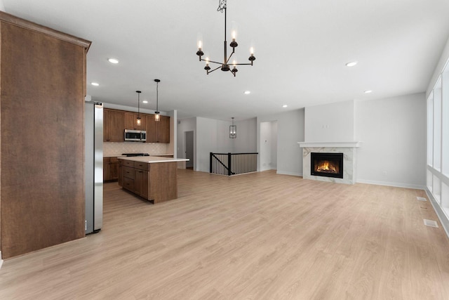 kitchen featuring hanging light fixtures, backsplash, stainless steel appliances, a center island, and light hardwood / wood-style floors