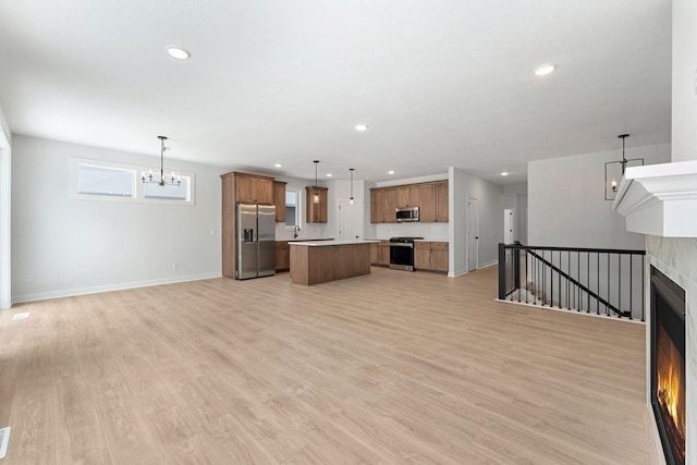 unfurnished living room featuring sink, a chandelier, and light hardwood / wood-style floors