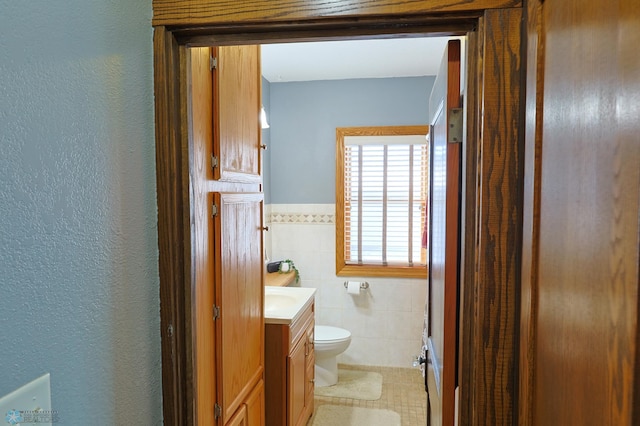 bathroom with vanity, toilet, and tile walls