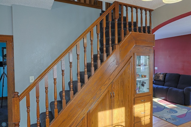 stairway with wood-type flooring and a textured ceiling