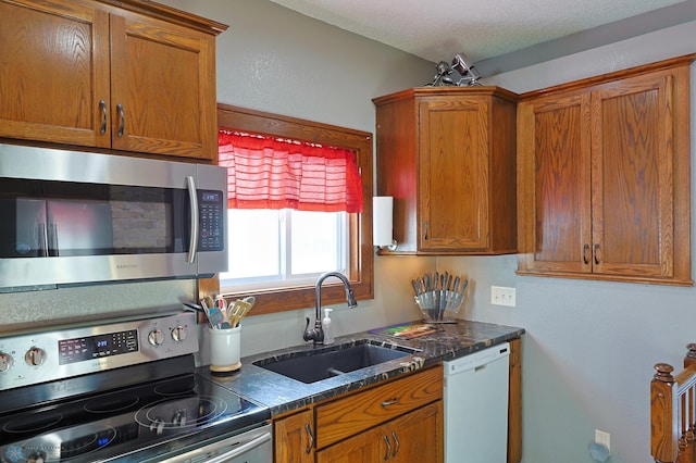 kitchen featuring appliances with stainless steel finishes, sink, dark stone countertops, and a textured ceiling