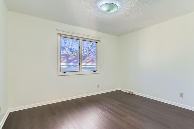 unfurnished room featuring dark hardwood / wood-style flooring and a textured ceiling