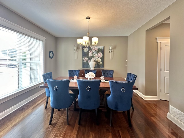 dining area with dark hardwood / wood-style flooring, a notable chandelier, and a textured ceiling