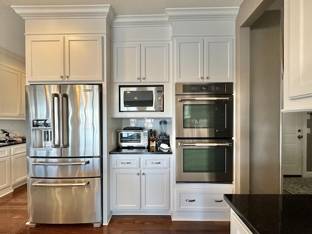 kitchen featuring white cabinets, stainless steel appliances, dark hardwood / wood-style flooring, and backsplash