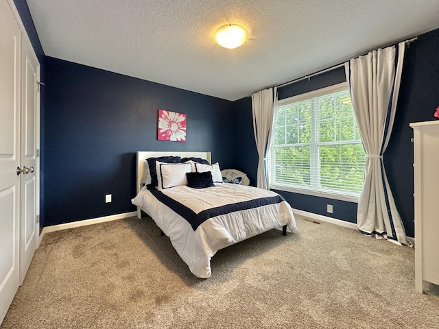 bedroom with light colored carpet and a textured ceiling