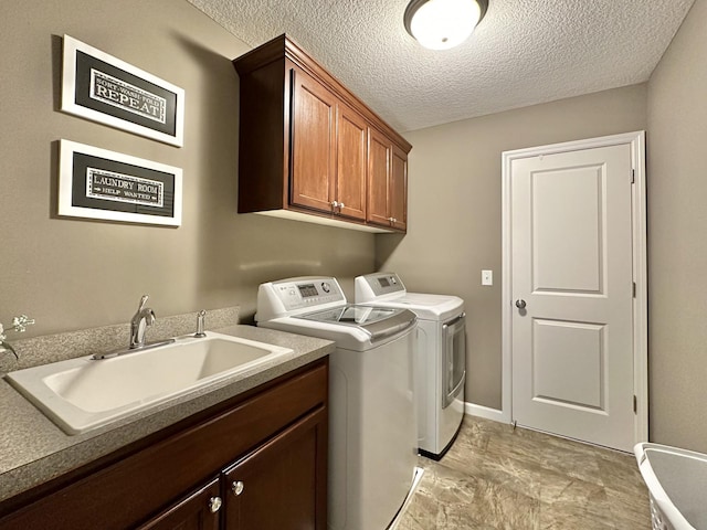 washroom featuring cabinets, washer and dryer, sink, and a textured ceiling