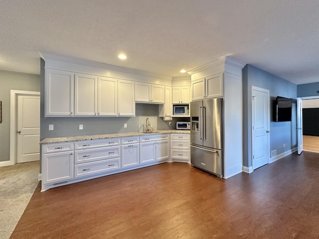 kitchen with sink, white cabinetry, stainless steel appliances, dark hardwood / wood-style floors, and light stone counters