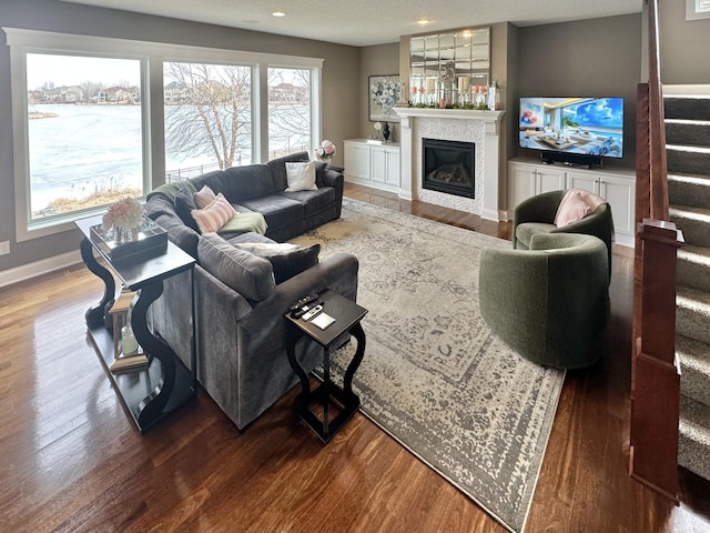 living area with recessed lighting, wood finished floors, baseboards, stairs, and a glass covered fireplace