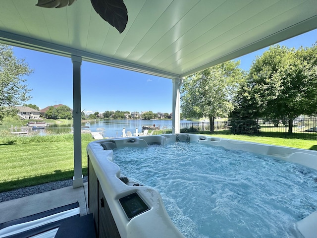 exterior space with a yard, a water view, fence, and a hot tub