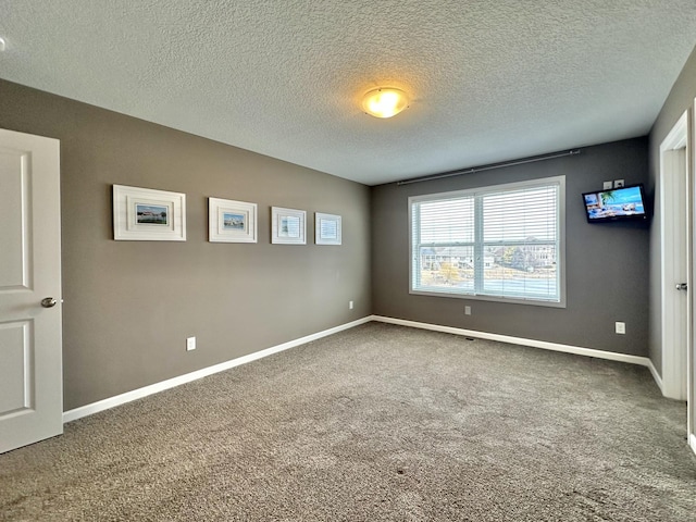 empty room with a textured ceiling, carpet flooring, and baseboards