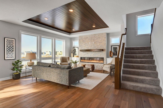 living room featuring a tray ceiling, a fireplace, hardwood / wood-style floors, and wood ceiling