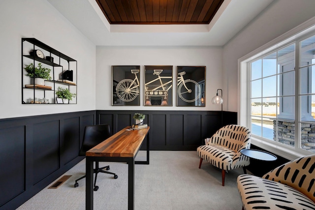 carpeted office with a raised ceiling and wood ceiling