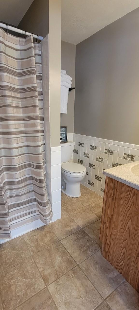 bathroom with vanity, tile walls, and toilet