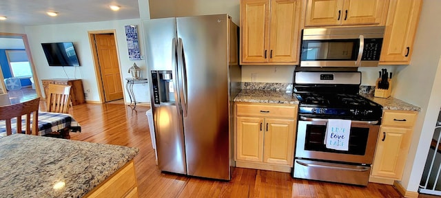 kitchen featuring light stone counters, hardwood / wood-style floors, and stainless steel appliances