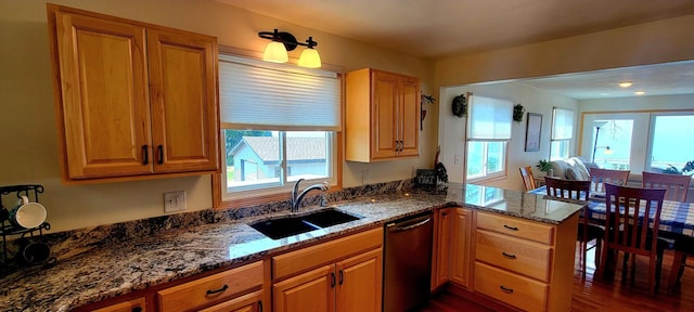 kitchen featuring dark stone counters, sink, stainless steel dishwasher, a wealth of natural light, and kitchen peninsula