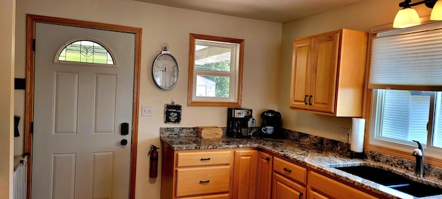 kitchen featuring sink, a wealth of natural light, and dark stone counters