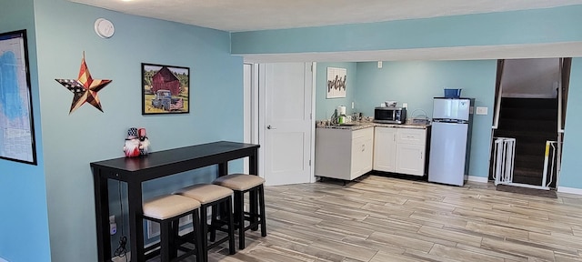 kitchen with white cabinetry, sink, appliances with stainless steel finishes, and light hardwood / wood-style flooring