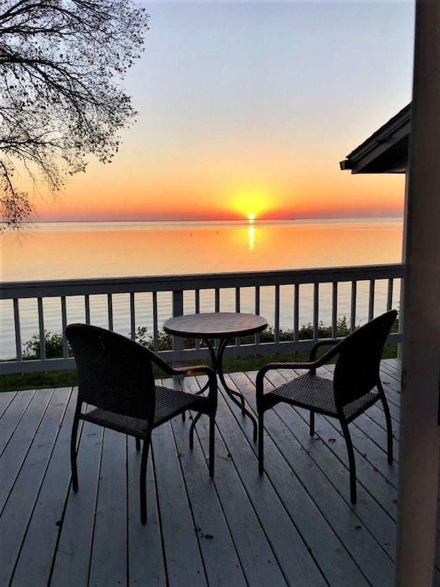 deck at dusk featuring a water view