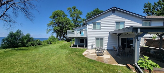 rear view of property featuring a lawn, a wooden deck, and a patio area