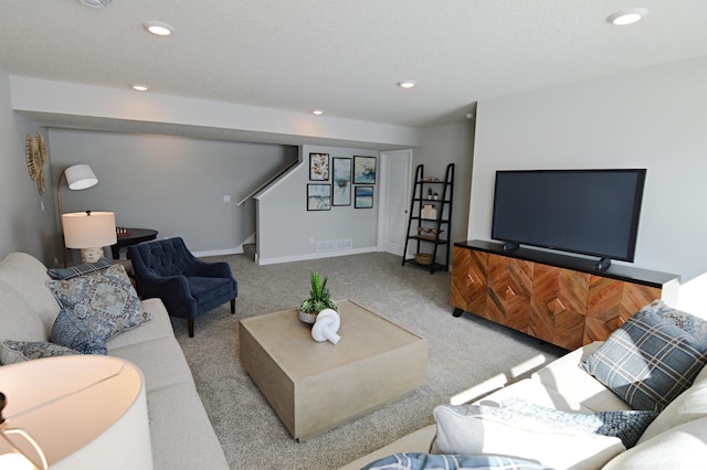 carpeted living room with a textured ceiling, recessed lighting, visible vents, baseboards, and stairs