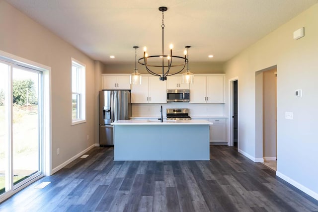 kitchen featuring a kitchen island with sink, white cabinetry, hanging light fixtures, and appliances with stainless steel finishes