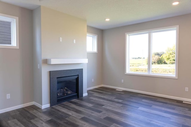 unfurnished living room with a textured ceiling and dark wood-type flooring