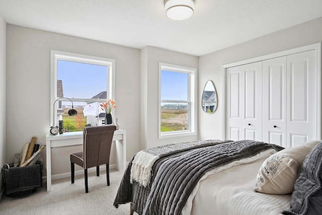 carpeted bedroom featuring multiple windows and a closet