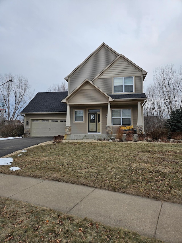 view of front of house featuring a front yard, an attached garage, stone siding, and driveway