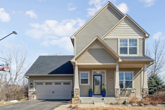 view of front of home featuring a porch, an attached garage, a shingled roof, stone siding, and aphalt driveway