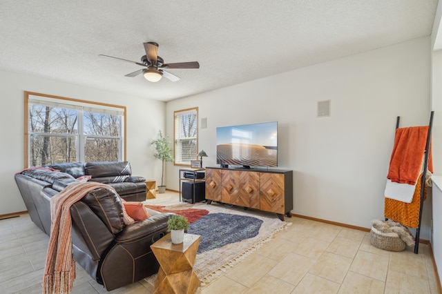 living area with baseboards, a textured ceiling, and ceiling fan