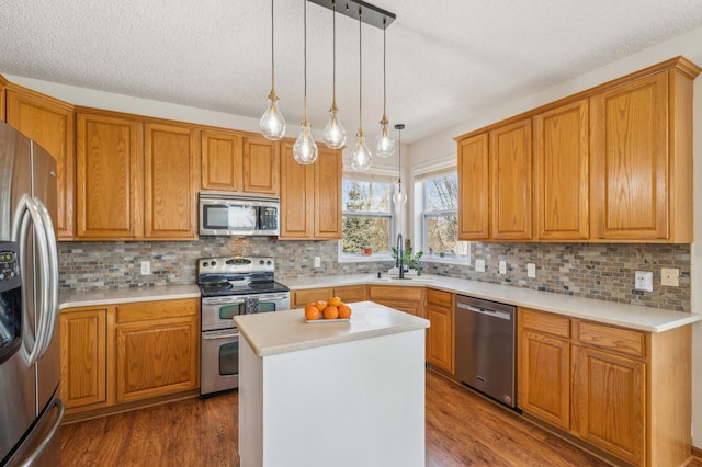 kitchen with a sink, stainless steel appliances, dark wood finished floors, and light countertops